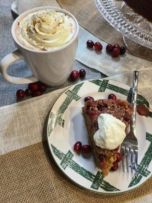 Cranberry upside down cake topped with whipped cream and a cup of hot cocoa