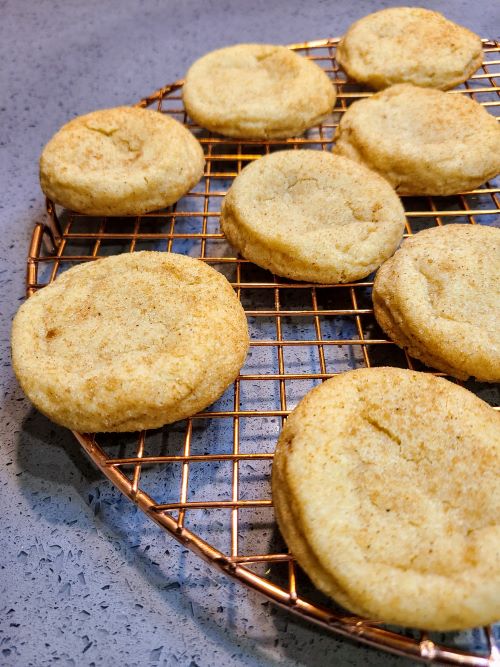 Snickerdoodles cooling on a bronze rack