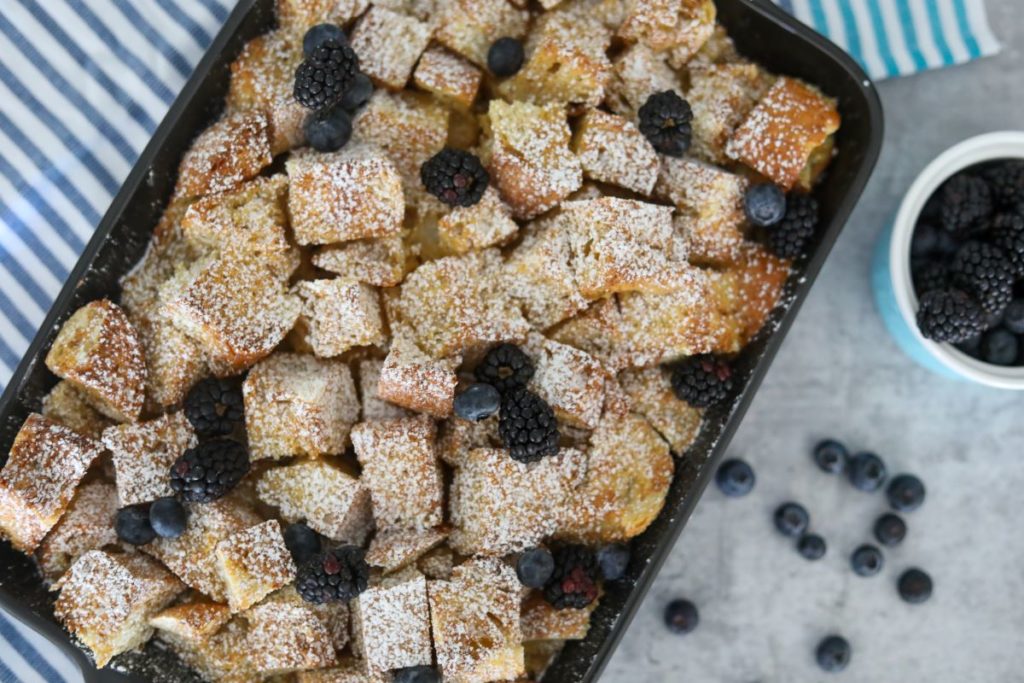 Baked French toast topped with powdered sugar and fresh fruit