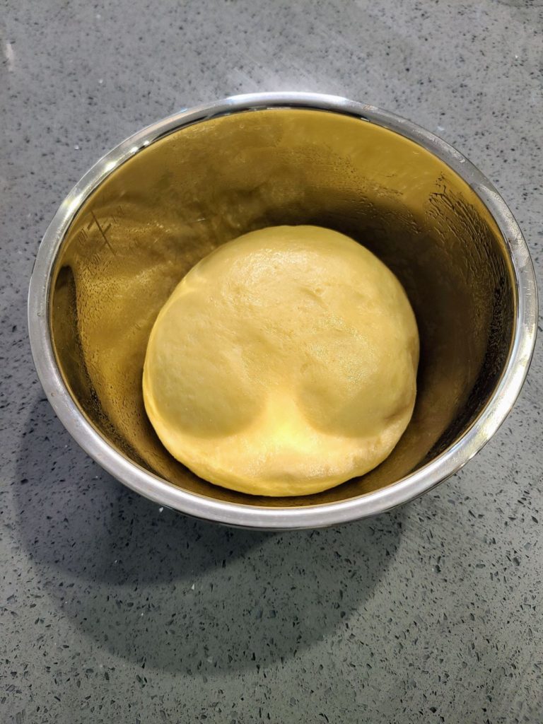 cinnamon maple roll dough ball in bowl before rising