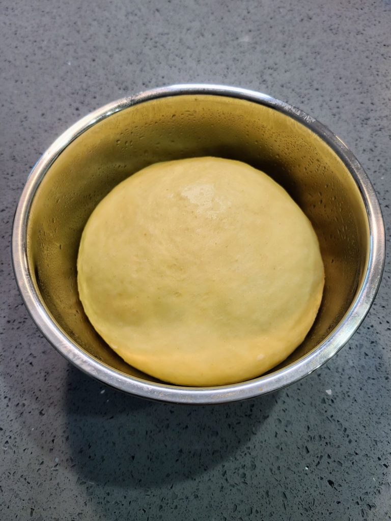 Risen ball of cinnamon maple roll dough in a bowl