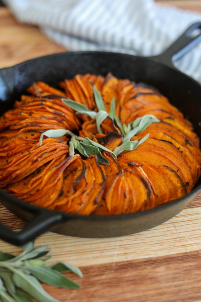 Cast iron pan with sage sweet potatoes and a towel