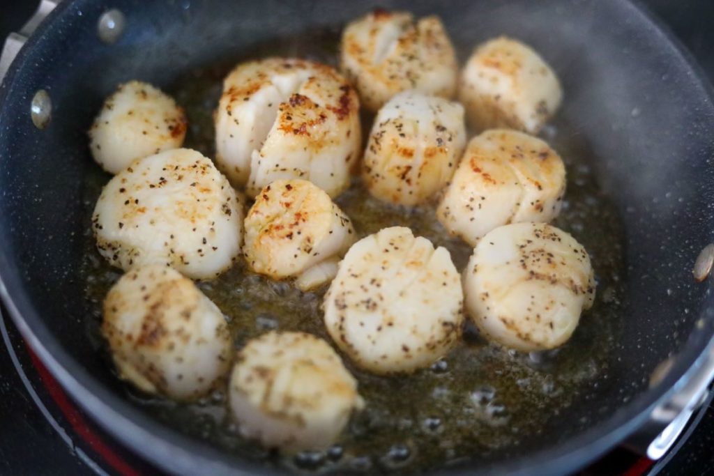 searing the other side of scallops in a pan