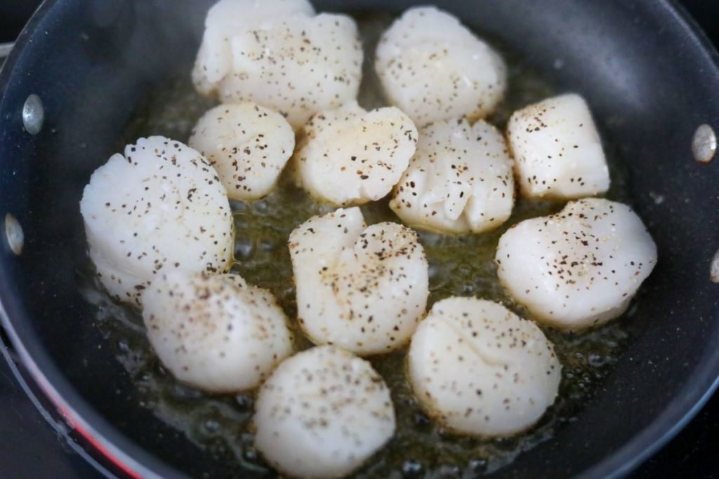 Searing the first side of scallops in a pan