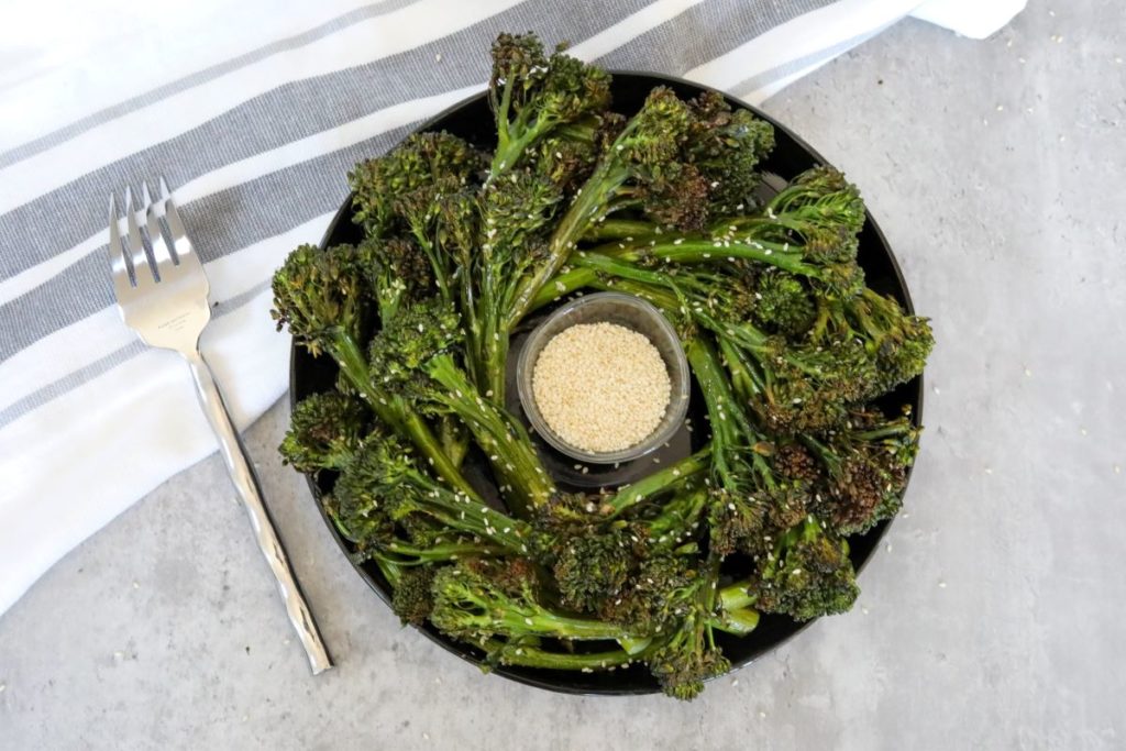 top down view of roasted broccolini wreath on a black plate
