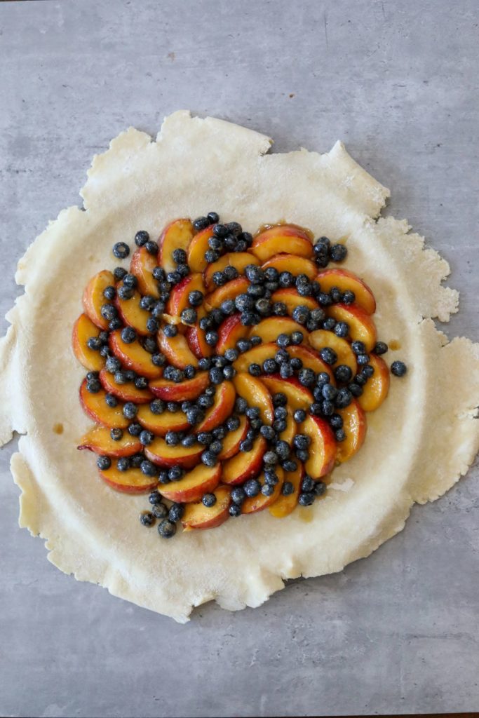 blueberry peach galette filling arranged on rolled out short crust pastry