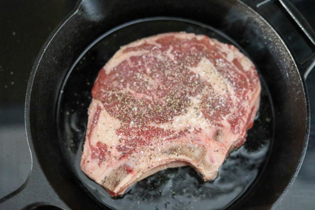 seasoned steak in a hot pan