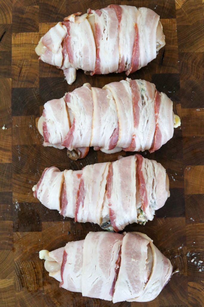 bacon wrapped stuffed chicken breasts on a cutting board