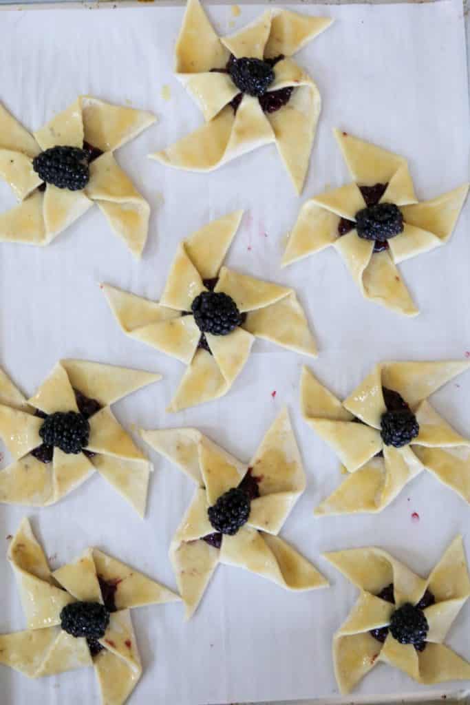 Unbaked blackberry pinwheels on a parchment lined sheet pan