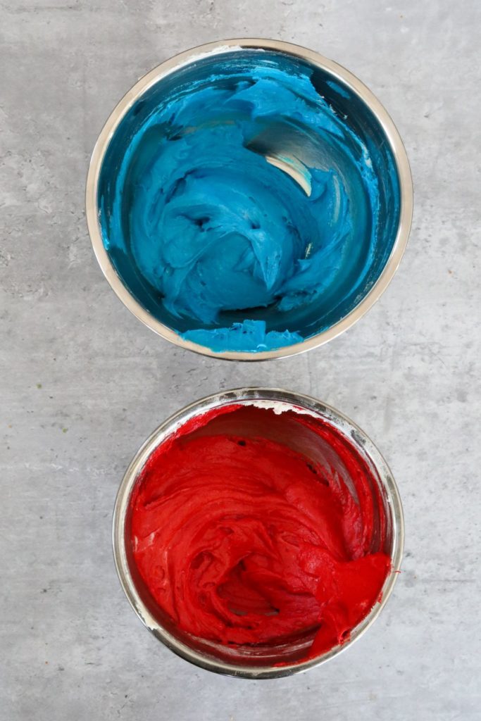 red and blue colored cake batter in 2 bowls