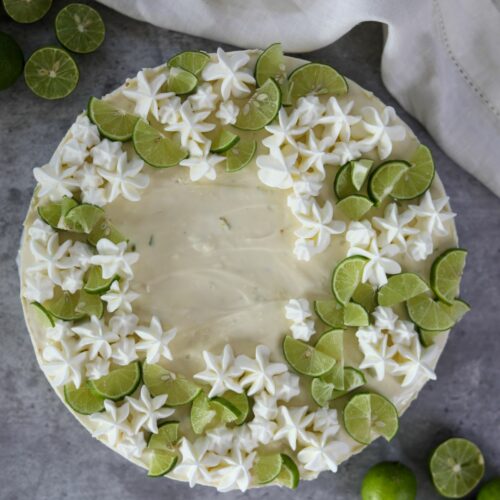 Whole key lime cheesecake surrounded by limes