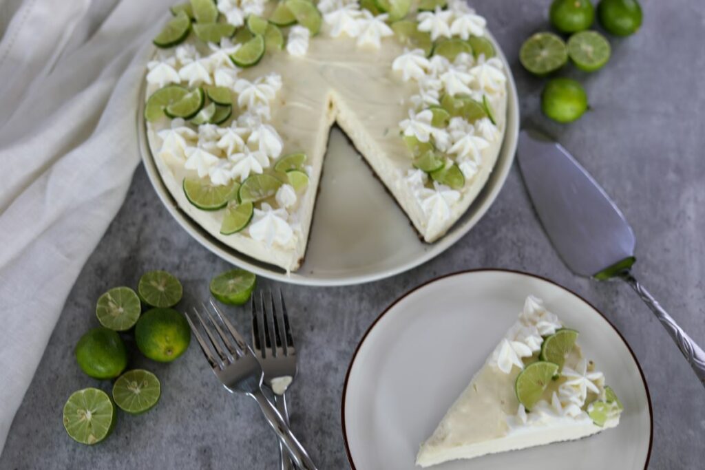 A key lime cheesecake on a white plate with a slice taken out