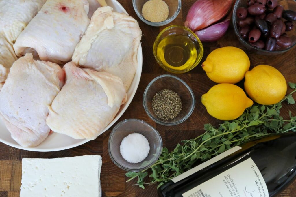 Ingredients for Greek chicken on a wood cutting board