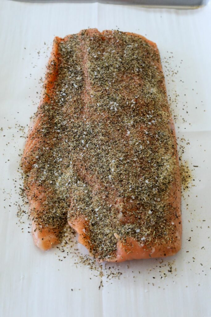 Salmon covered in seasoning on a lined sheet pan