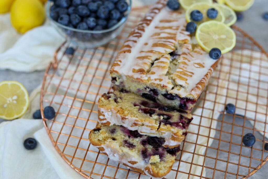 Sliced iced blueberry lemon loaf cake on a cooling rack