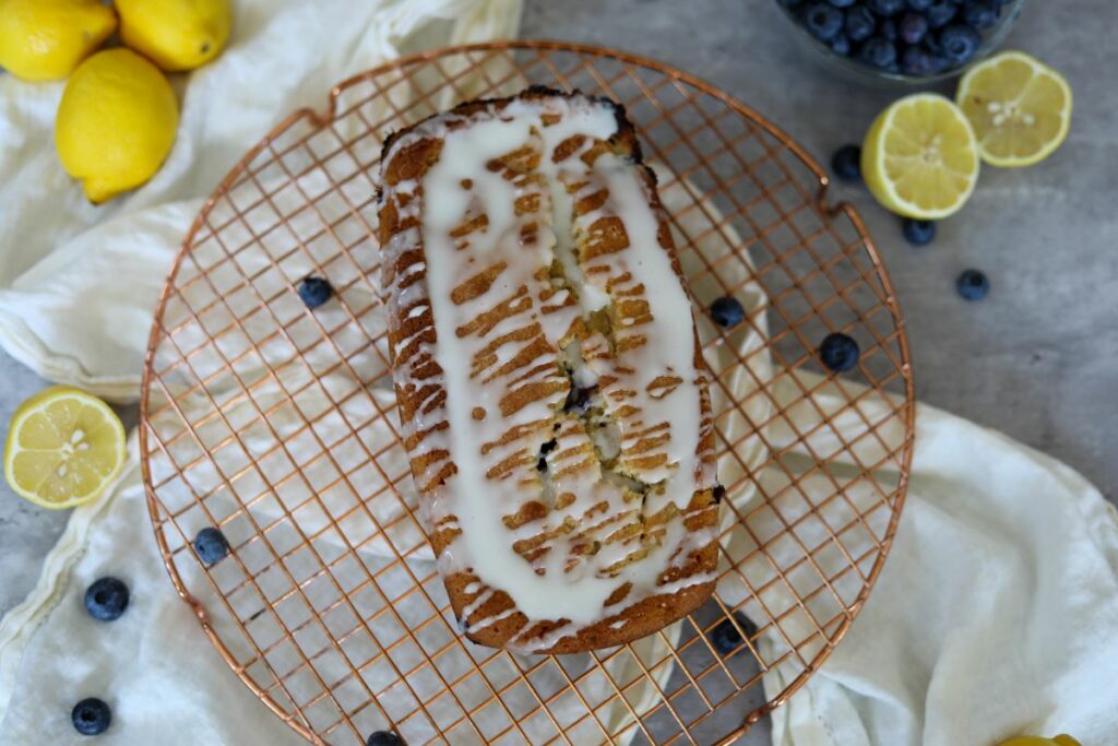 Iced blueberry lemon loaf cake on a cooling rack