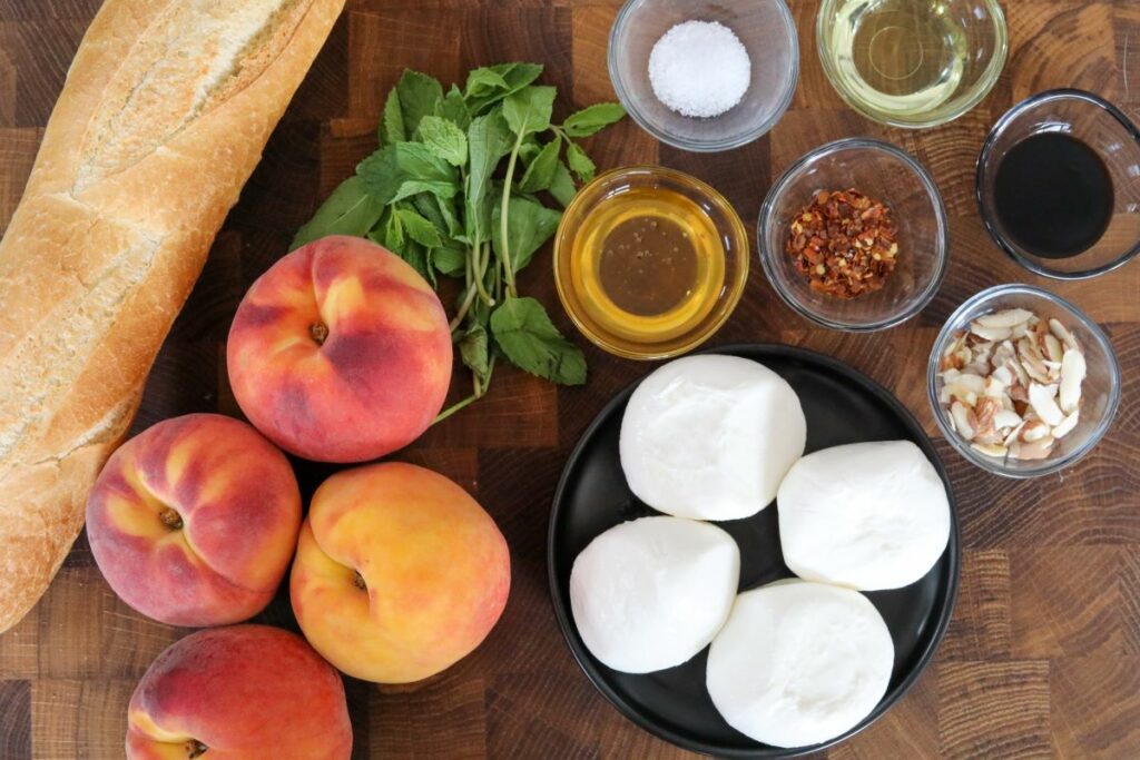 Ingredients for grilled peach crostini on a wooden board.