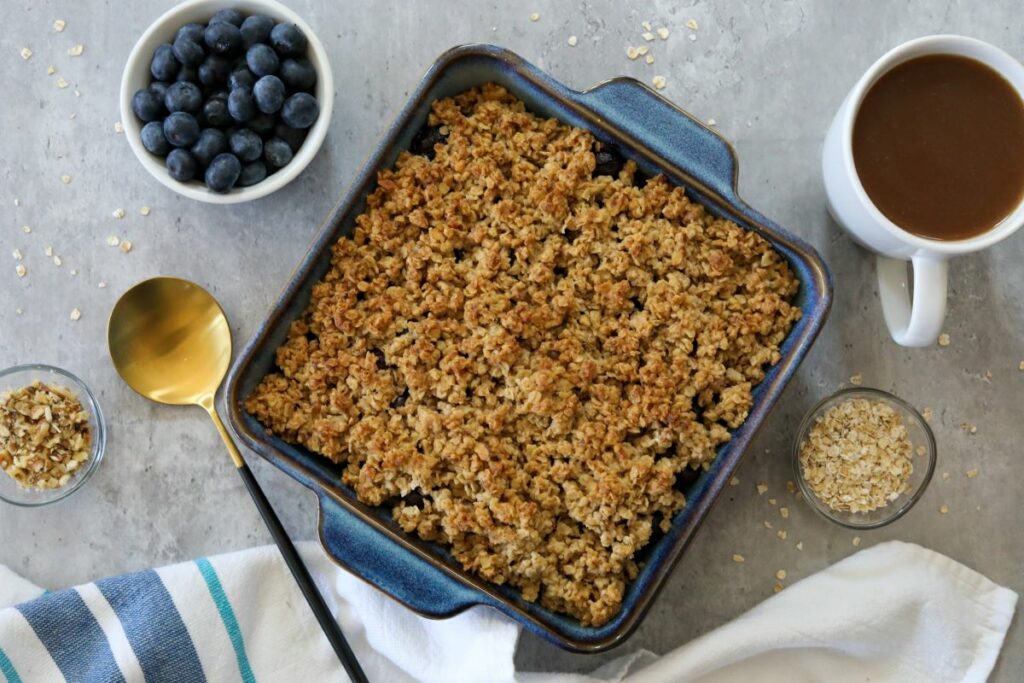 Cooling blueberry crisp in a baking dish with a cup of coffee