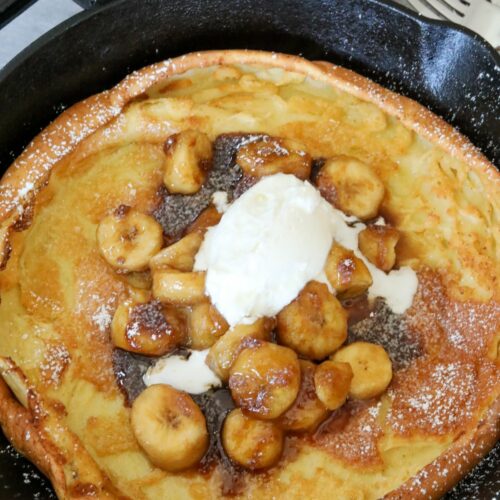 A close up of a bananas foster dutch baby in an iron skillet