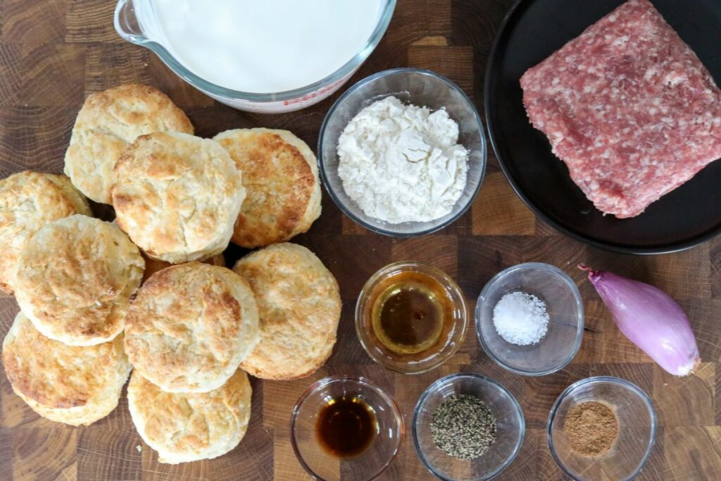 Ingredients for biscuits and gravy on a wooden cutting board