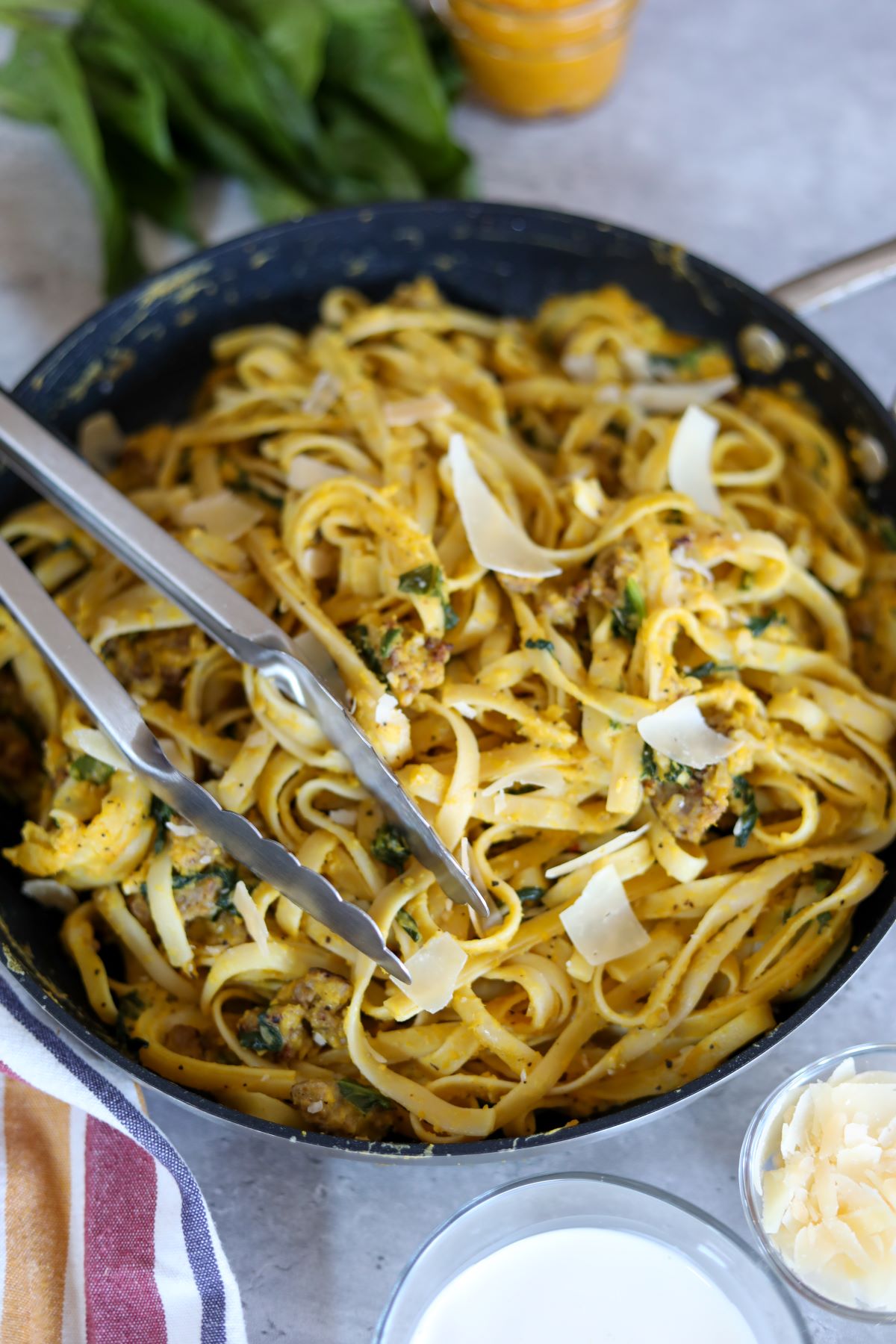pumpkin pasta in a pan with tongs