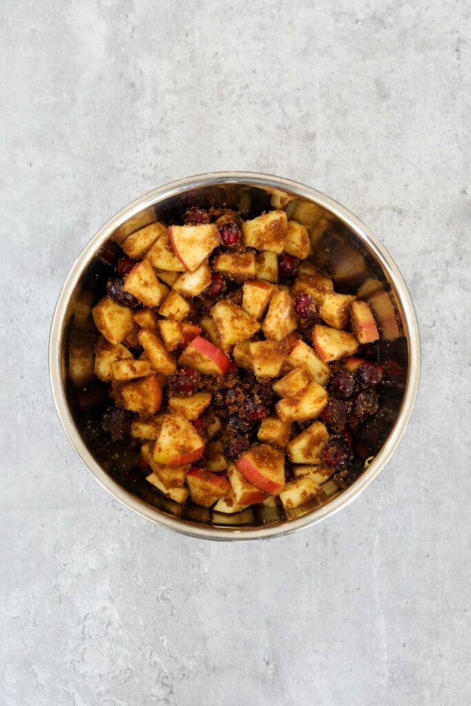 A bowl with mixed apples and cranberries with brown sugar