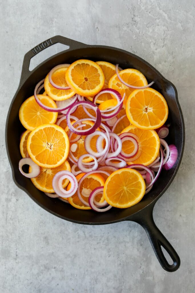 slices of orange and onions on a cast iron skillet