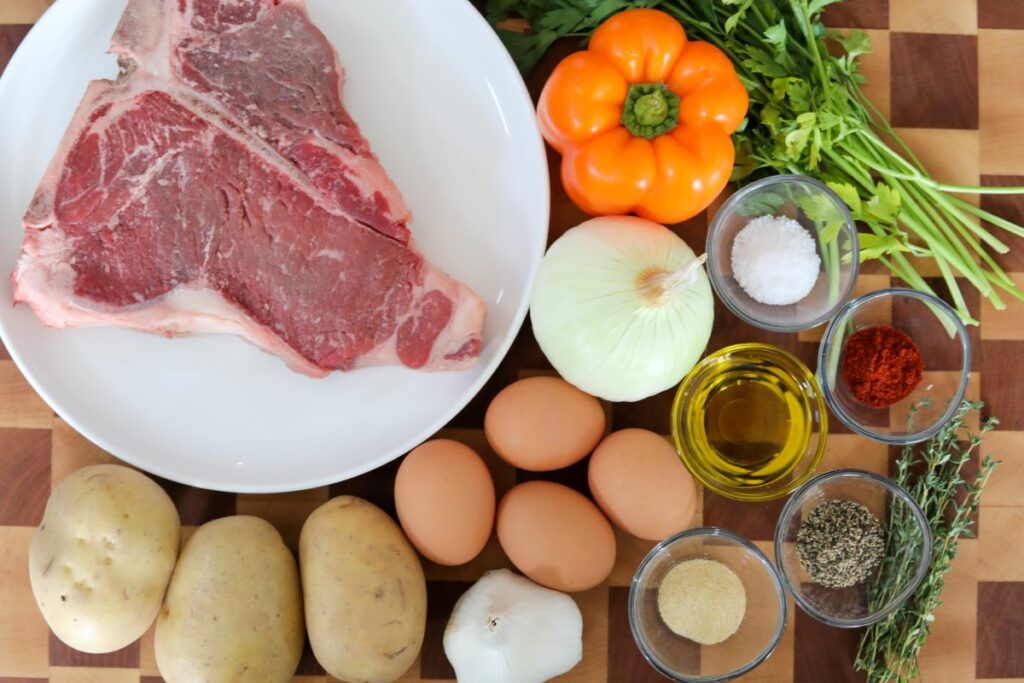 Steak and potato hash ingredients on a wooden cutting board