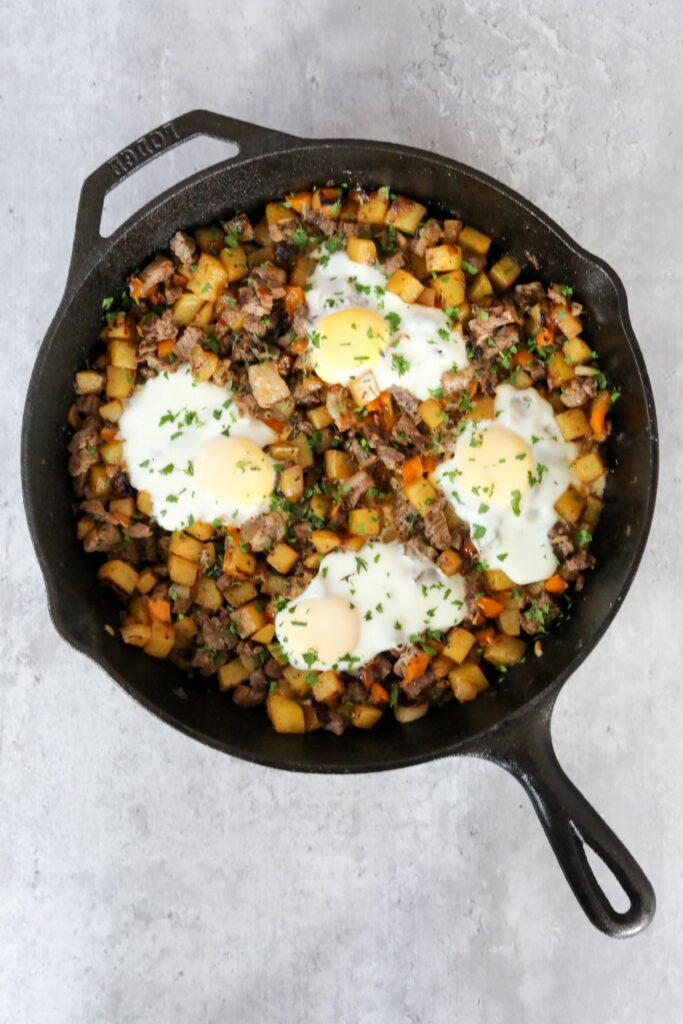Steak and potato hash with eggs in a cast iron skillet