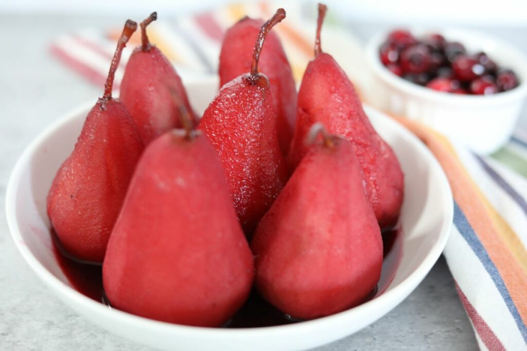 A white bowl with several poached pears in it