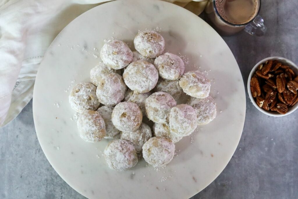 A mound of Mexican wedding cookies on a white platter