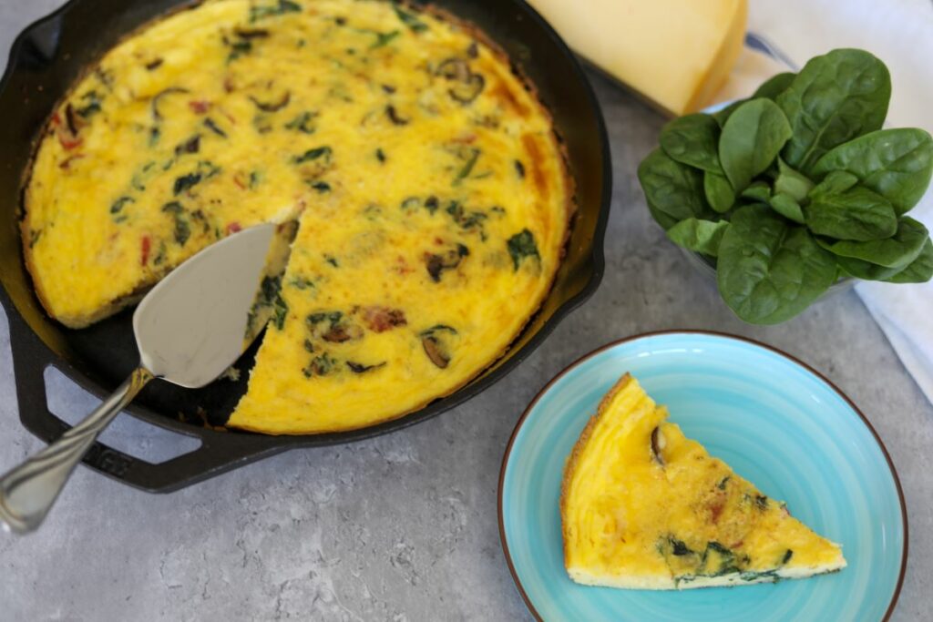 A slice of spinach and mushroom frittata on a plate