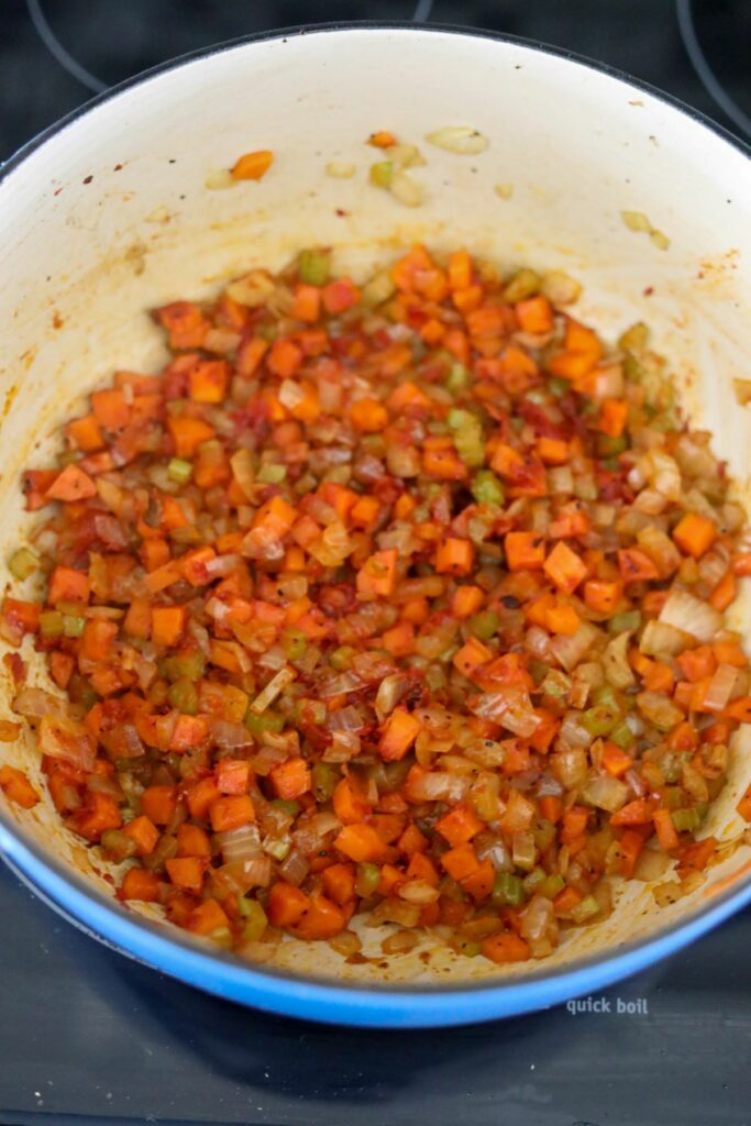 Tomato paste added to mirepoix in a Dutch oven