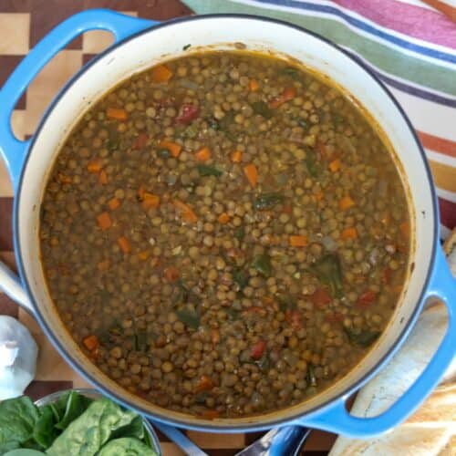 A pot of lentil soup with a baguette