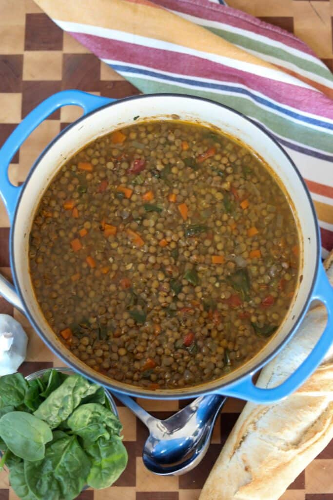 A pot of lentil soup with a baguette