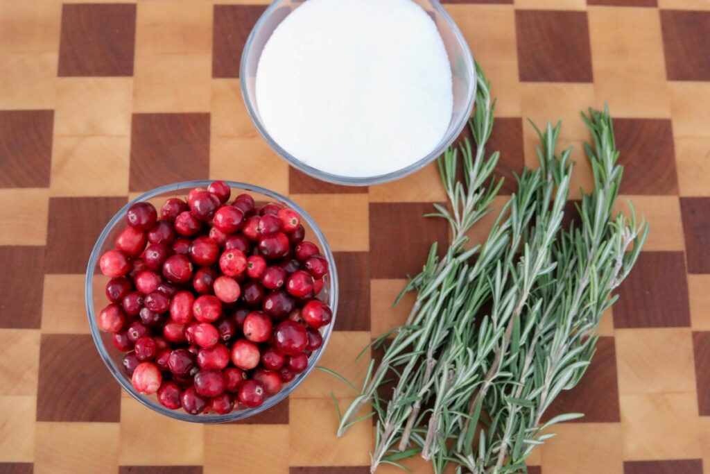 Ingredients for sugared cranberries on a wooden cutting board