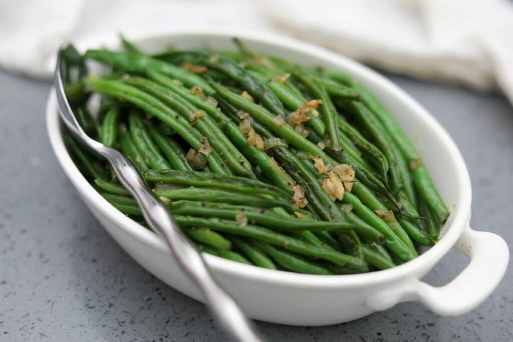 A white bowl with sautéed green beans