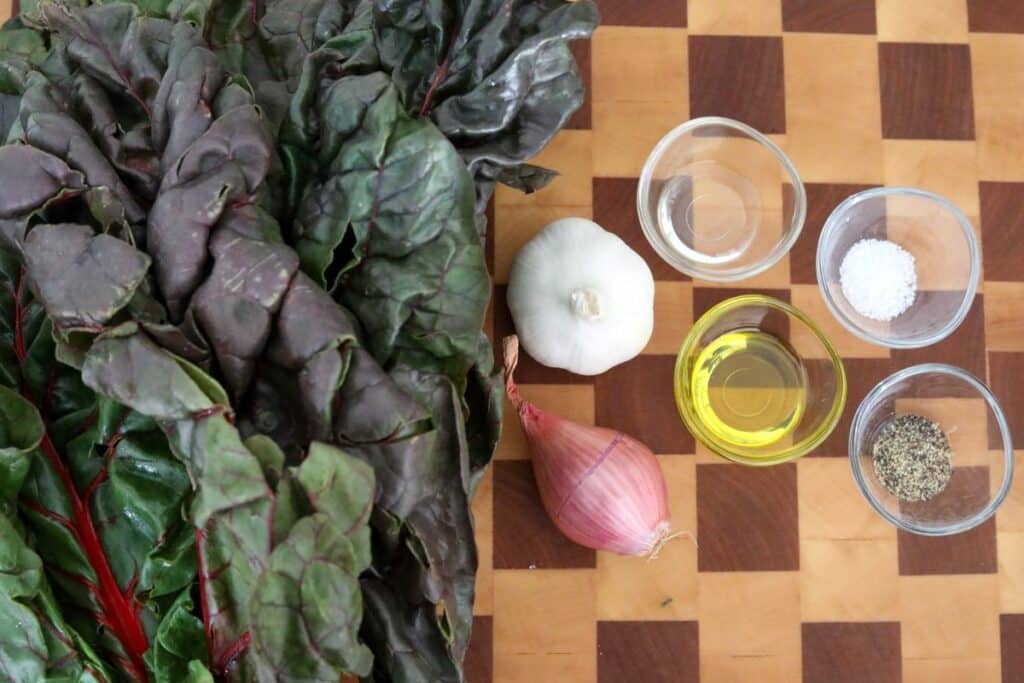 Ingredients for sauteed Swiss chard on a wooden cutting board