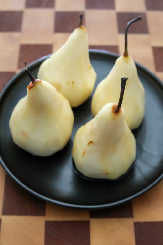 Cored and peeled pears on a black plate