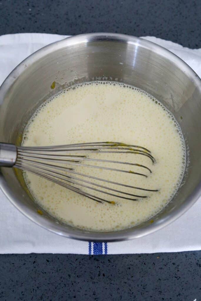Whisked egg yolk mixture with milk in a metal bowl
