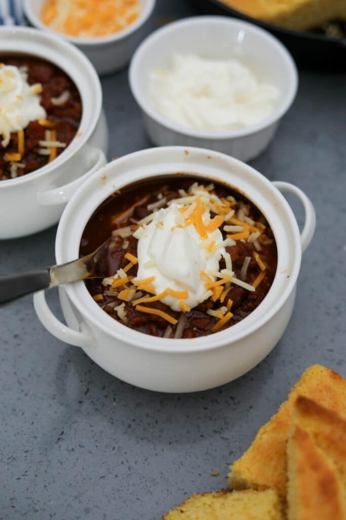 To crocks of chili with sour cream and cheese