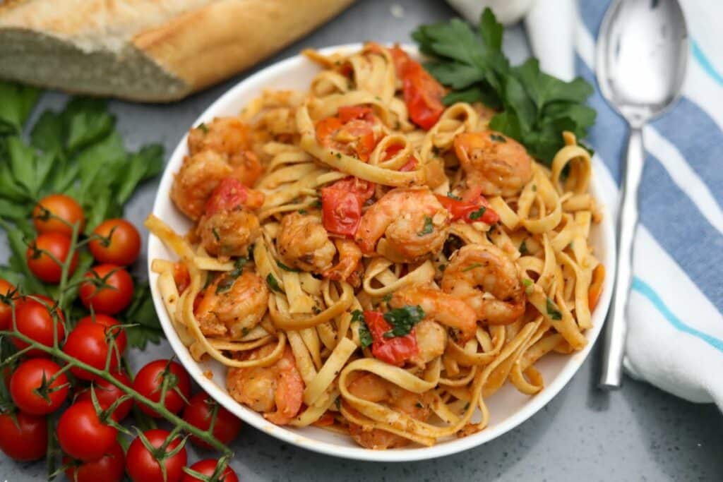 tomato and shrimp pasta ready to serve in a white bowl