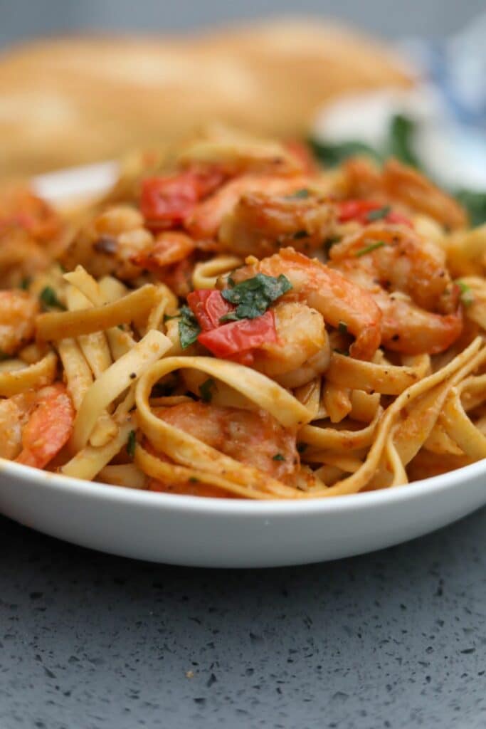 A white bowl with tomato and shrimp pasta