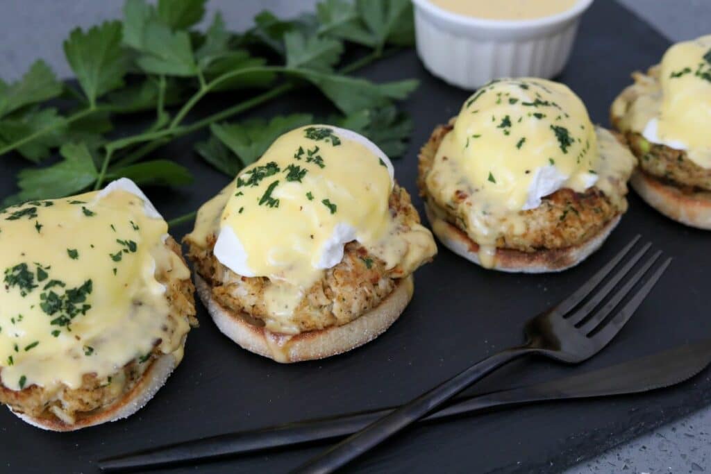 Four crab cake benedict on a slate plate.