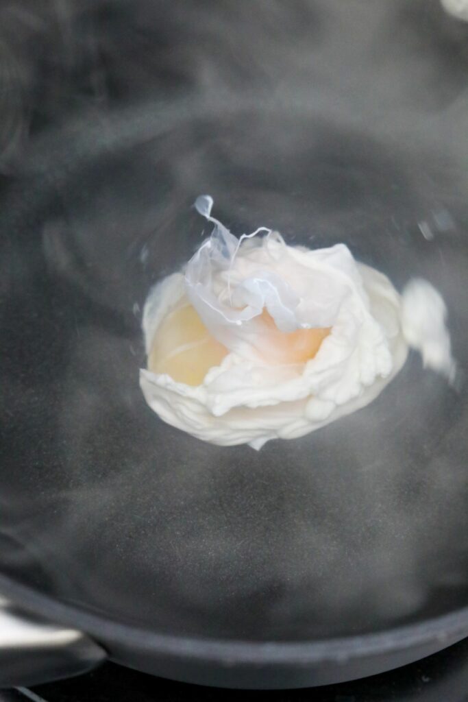Egg dropped into a simmering water vortex