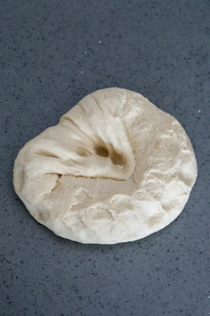 Pressing the first stretch back into the dough ball