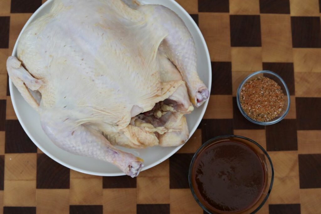 Ingredients for whole barbecue chicken on a wooden cutting board