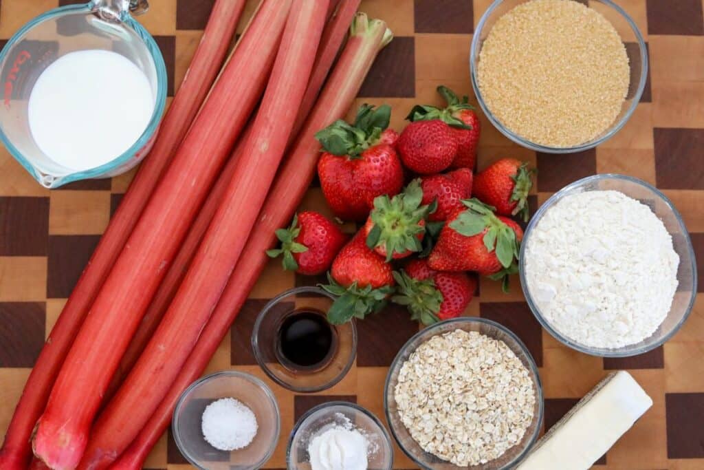 Ingredients for strawberry rhubarb cobbler on a wooden cutting board