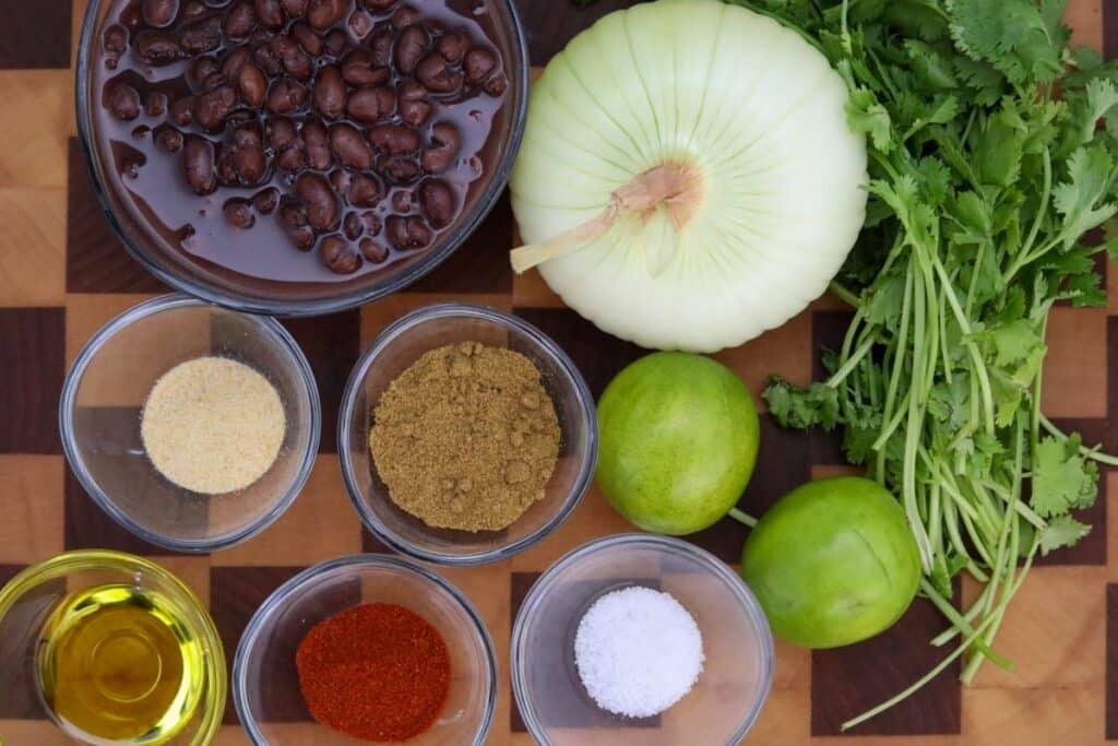 Ingredients for Mexican black beans on a wooden cutting board