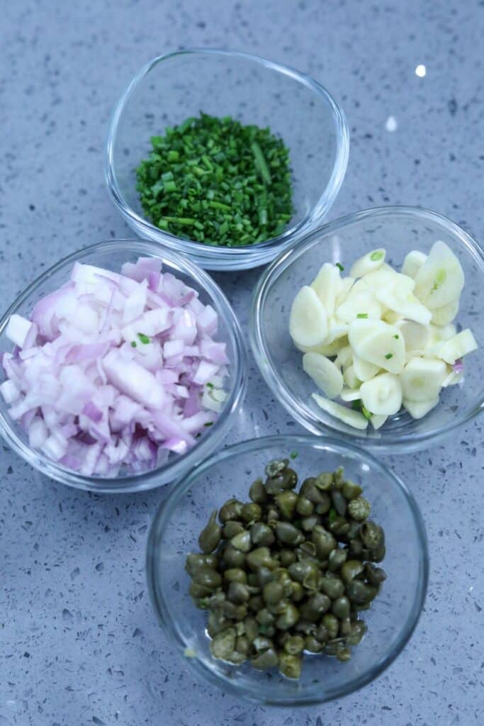 Chopped chives, garlic, shallots and capers in bowls